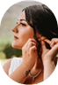 Young woman with dark hair adjusting a delicate earring at her ear