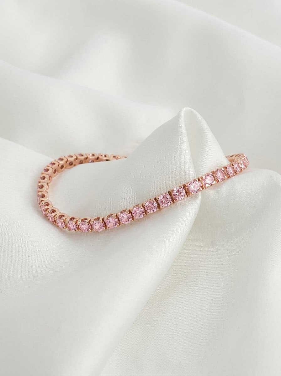 Rose gold tennis bracelet with round pink cubic zirconia prong settings on white satin fabric.