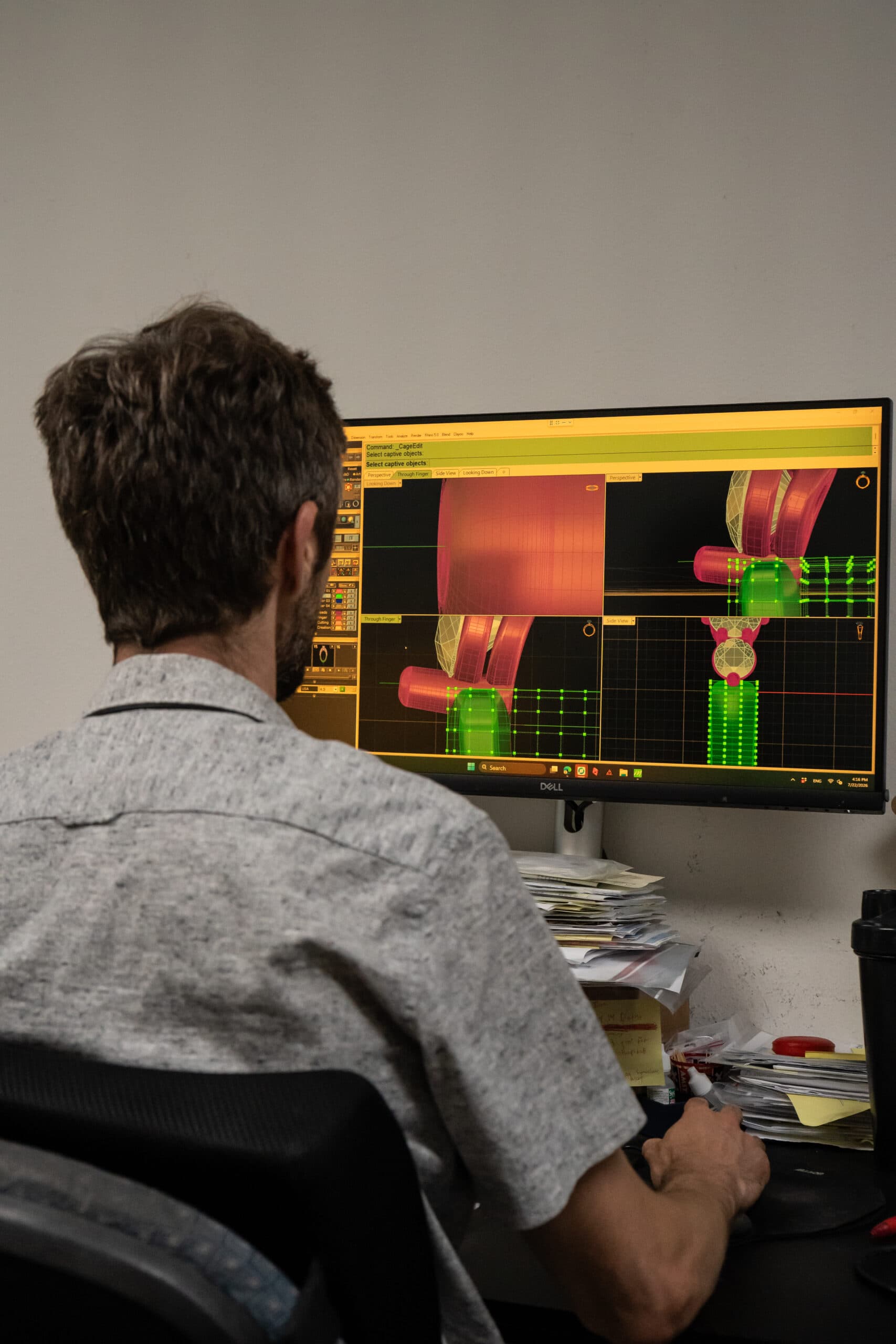 Jewelry designer working at desk with 3D CAD ring model on Dell monitor