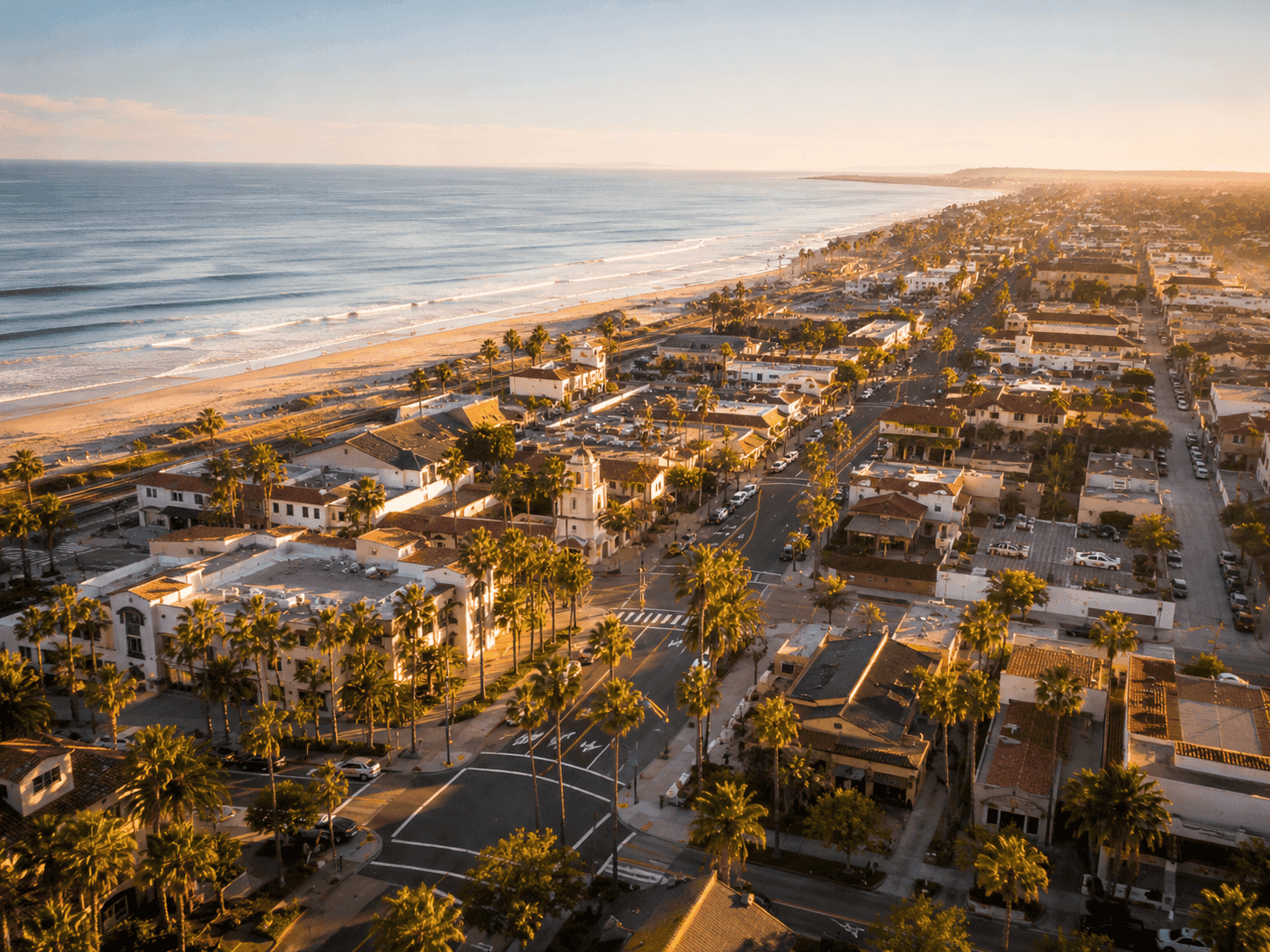 Aerial view of a sunny California coastal town with palm-lined streets and sandy beach