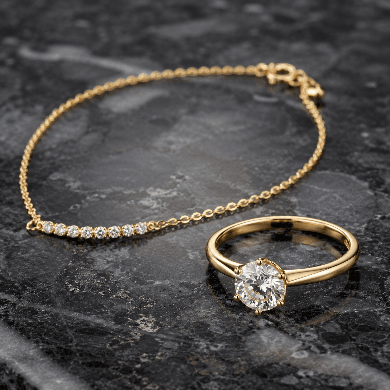 Yellow gold diamond solitaire ring and diamond bar bracelet on dark granite