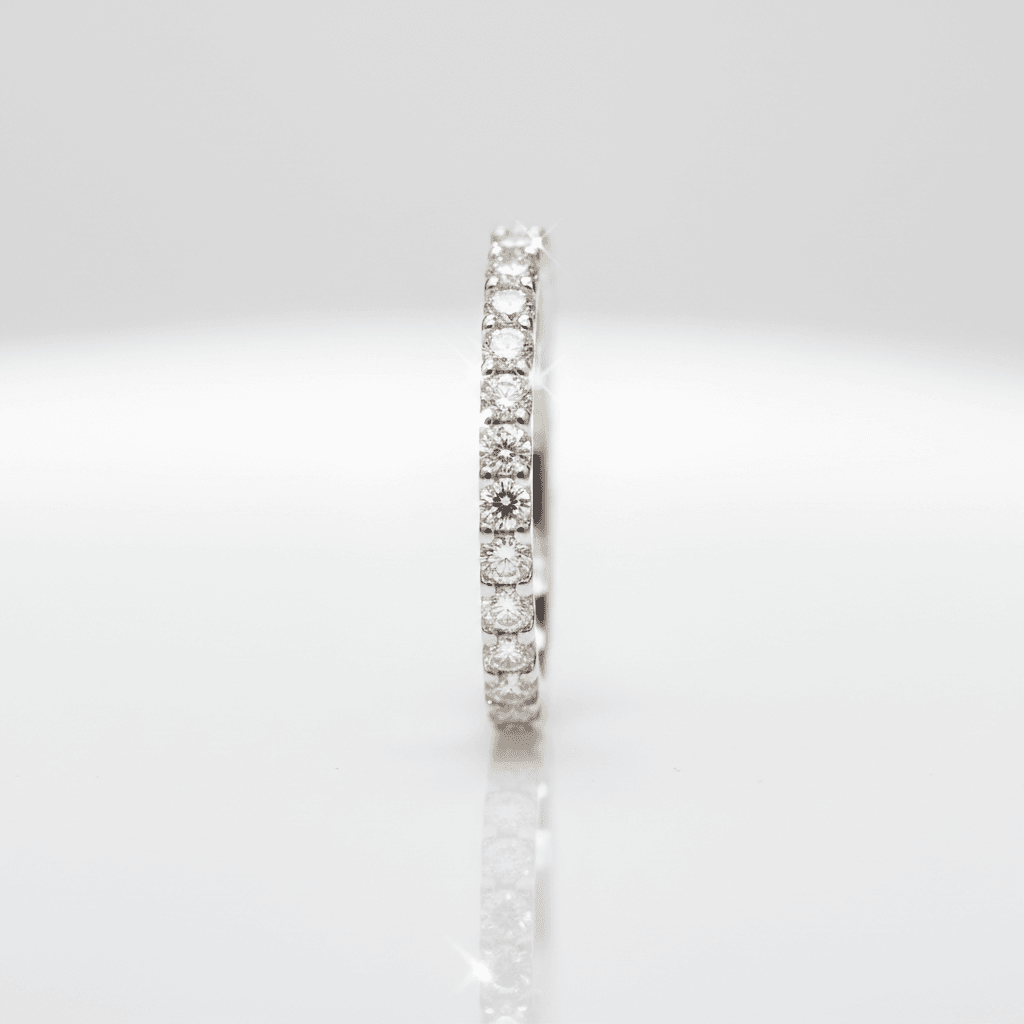 Diamond eternity band standing upright on a reflective white surface