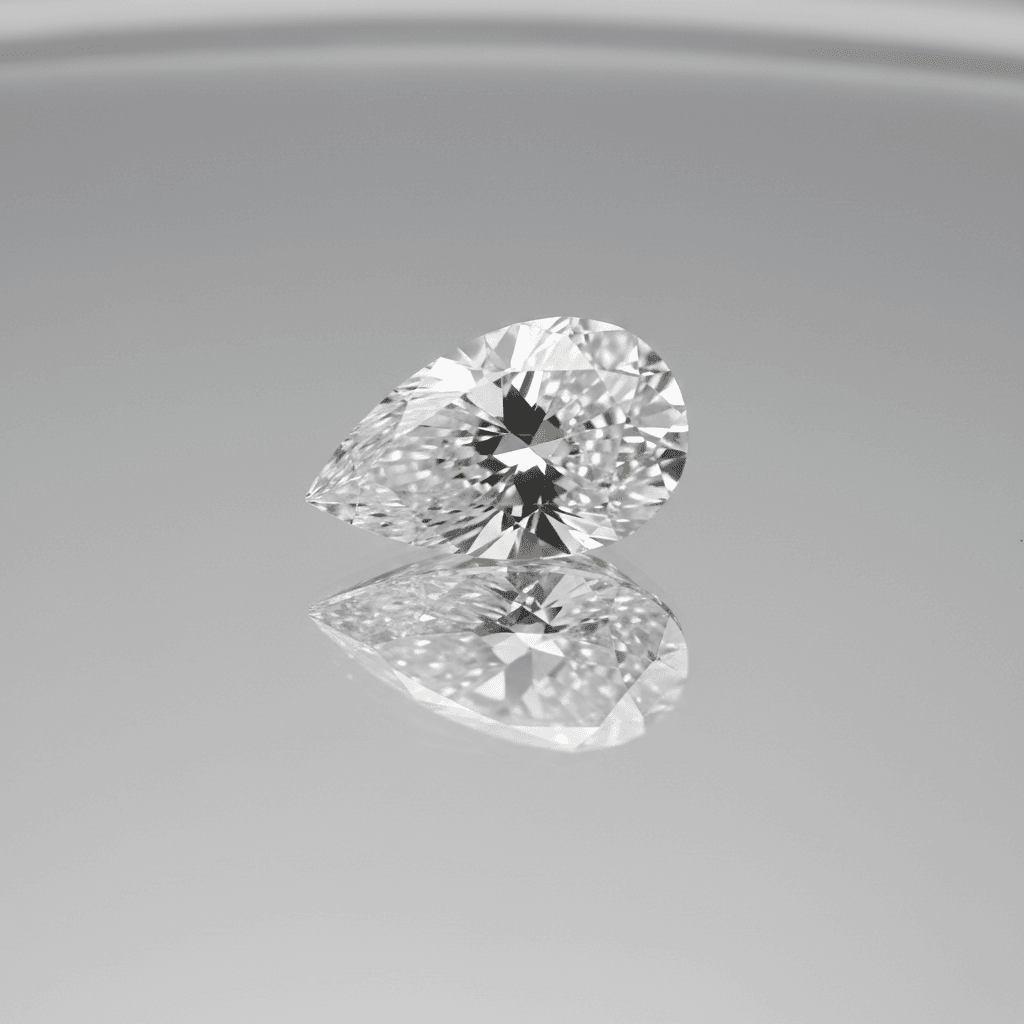 Loose pear-cut diamond with brilliant facets resting on a reflective grey surface