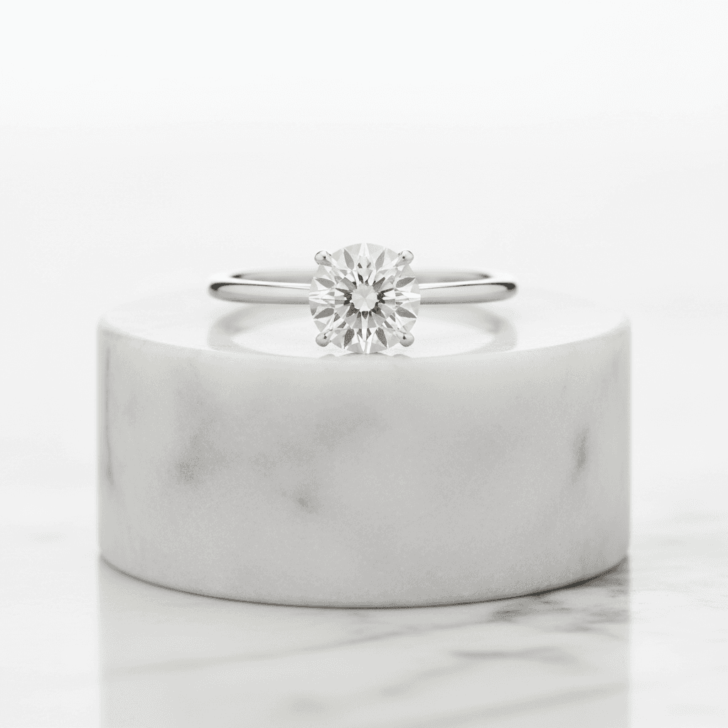 Round diamond solitaire engagement ring with six-prong setting on marble pedestal