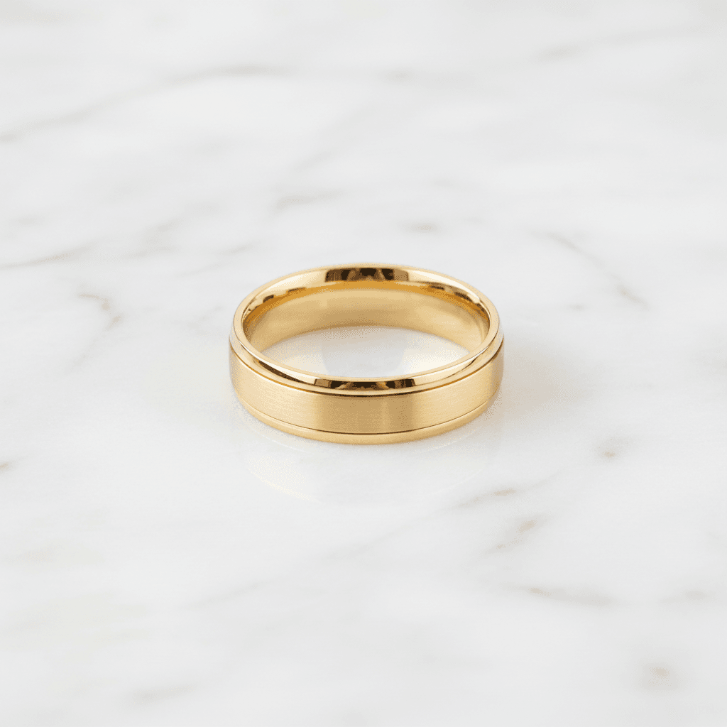 Yellow gold wedding band with brushed centre and polished stepped edges on marble